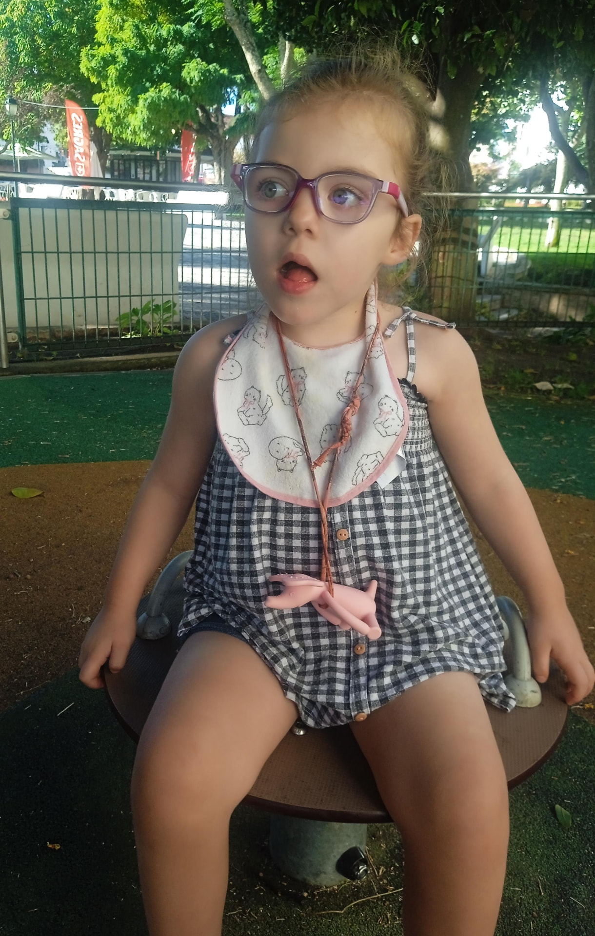 Fabiana, a 3-year-old girl, sitting on a playground spinner