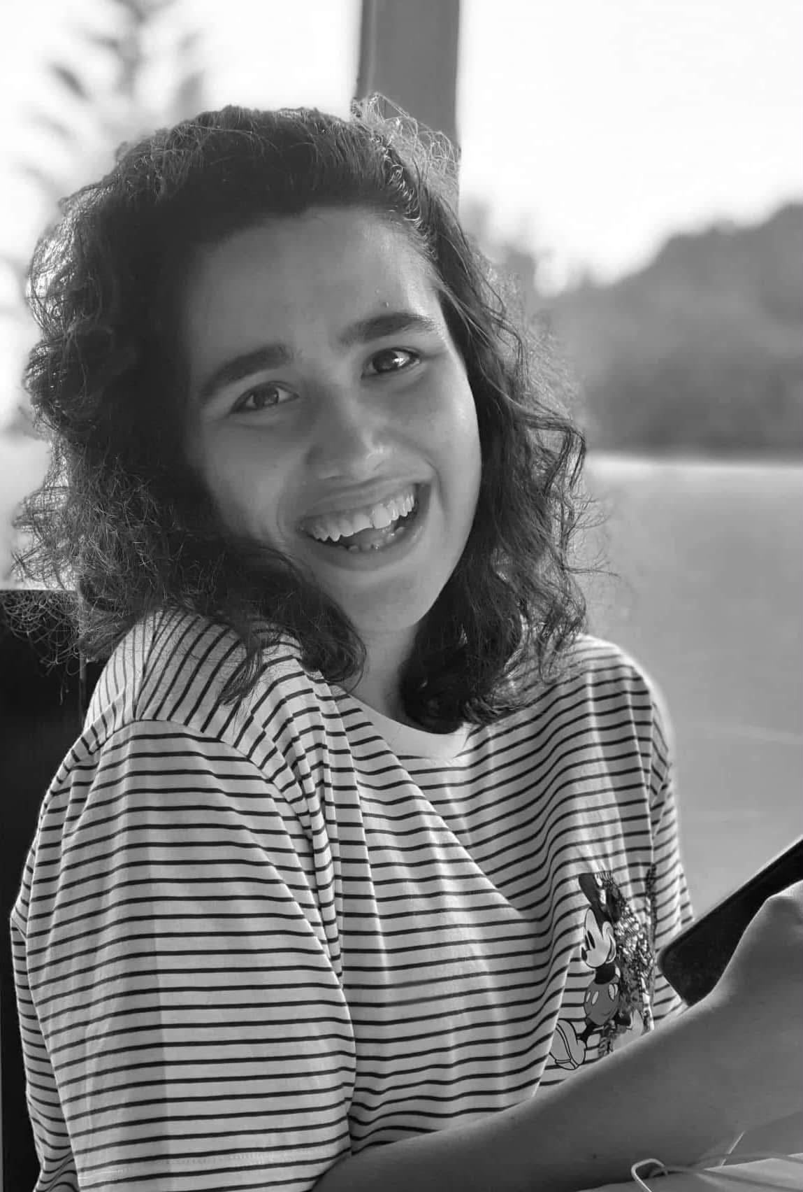 Laura, a young adult, in a black and white portrait smiling